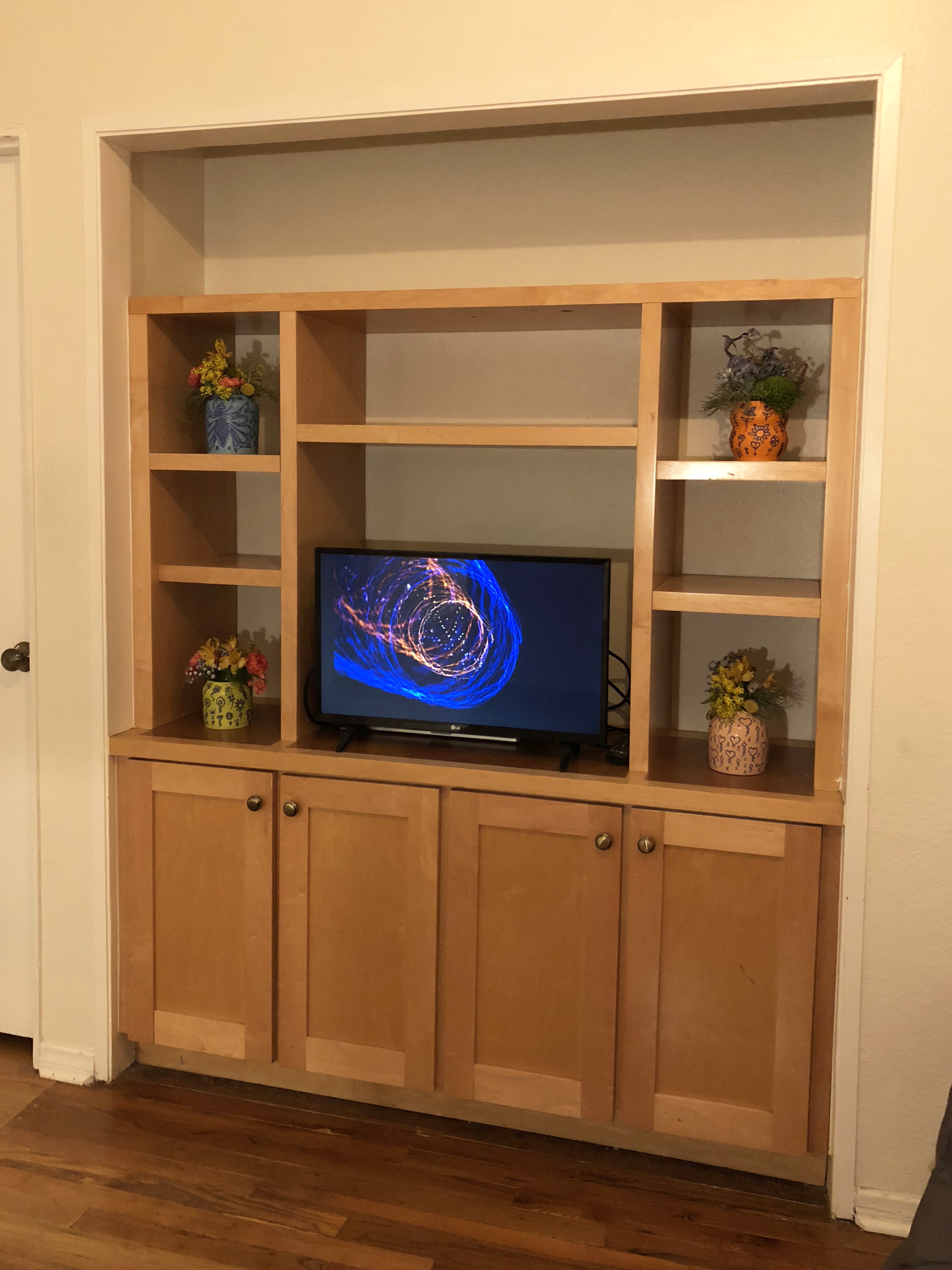 Entertainment console with a television in the center and four ceramic vases around it